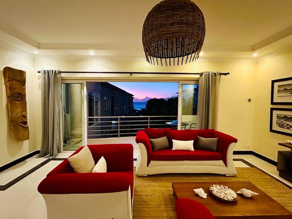 a living room with red and white furniture and a balcony at Sea view Ginger apartment in Pointe aux Biches