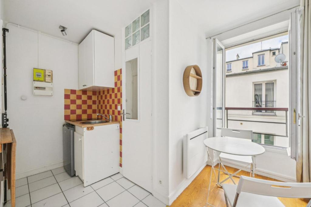 une petite cuisine avec une petite table et une fenêtre dans l'établissement L’Insoupçonné, à Paris