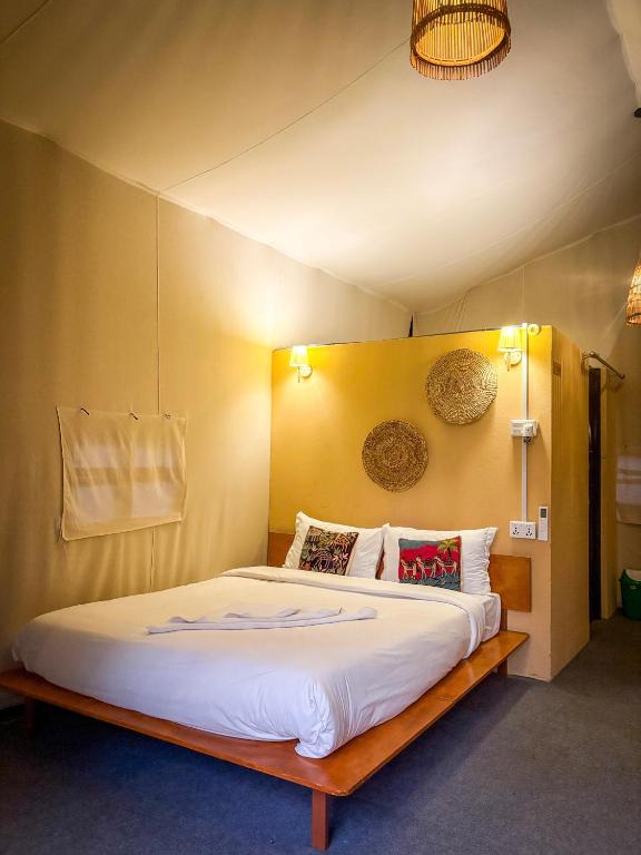 a bedroom with a large bed with white sheets and pillows at Hotel Tharu Garden And Beer Bar in Chitwan