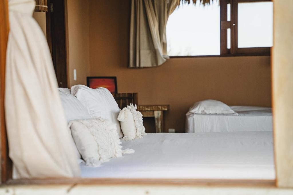 a bedroom with two beds with white pillows at Tatadise in Tatajuba