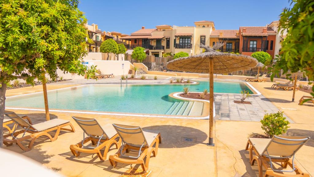 a swimming pool with chairs and an umbrella at Villa Luisa - Relax with Ocean View and Pool in San Miguel de Abona