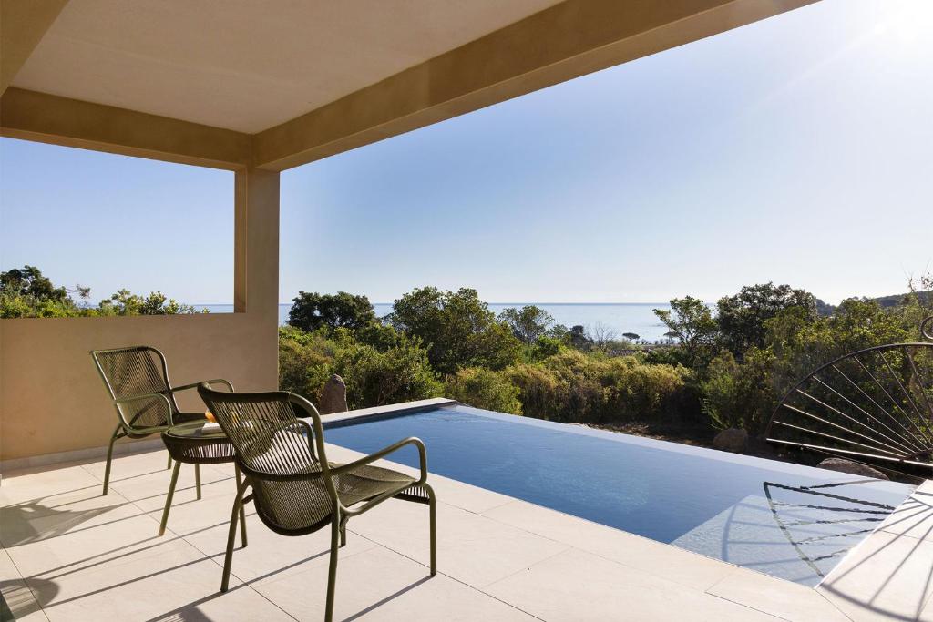 a patio with two chairs and a swimming pool at Hôtel & Spa A Cala - Suites Piscines Privées - Adults Only in Conca