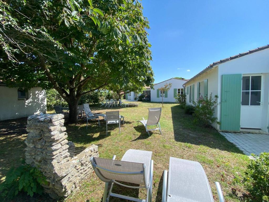 une cour avec des chaises, une table et un arbre dans l'établissement La Villa du Clocher, à Saint-Clément-des-Baleines
