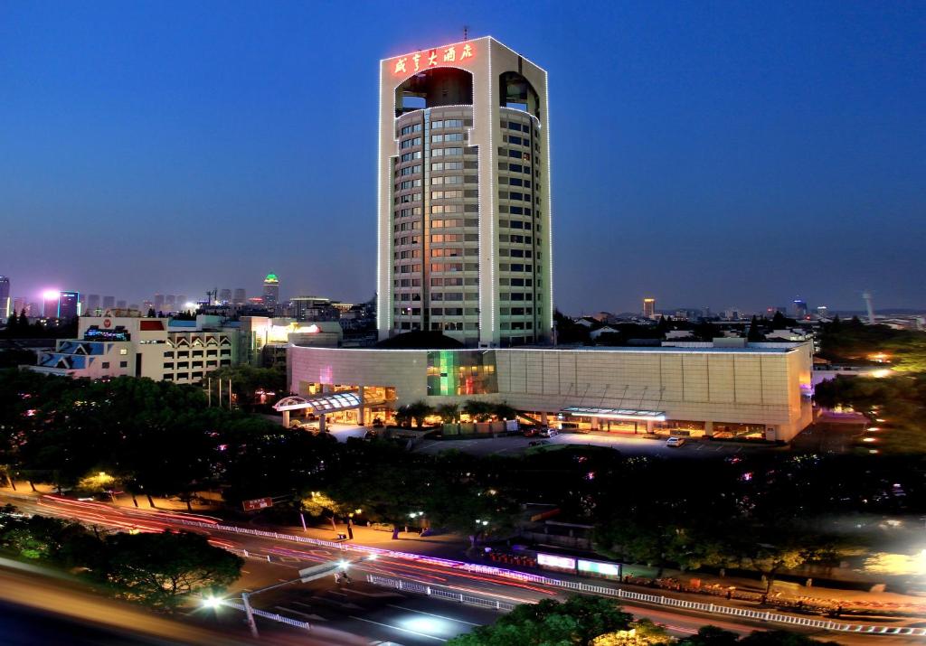 un grand bâtiment avec un panneau sur lui la nuit dans l'établissement Xian heng Hotel, à Shaoxing