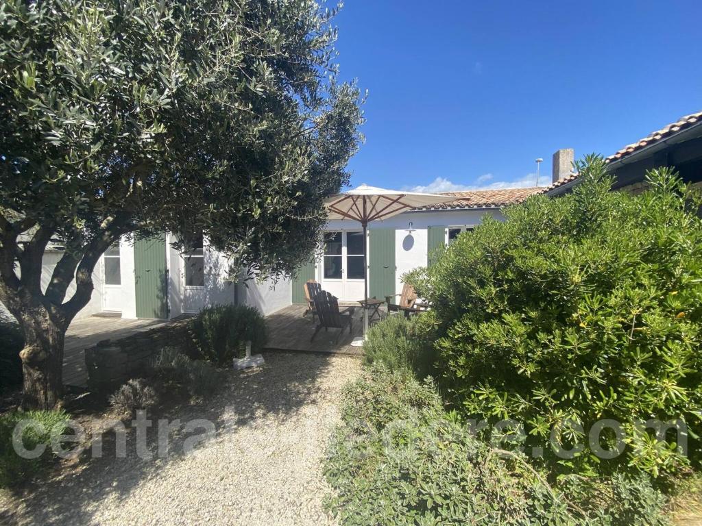 a small white house with a tree and bushes at La Villa de Hurlevent in Les Portes