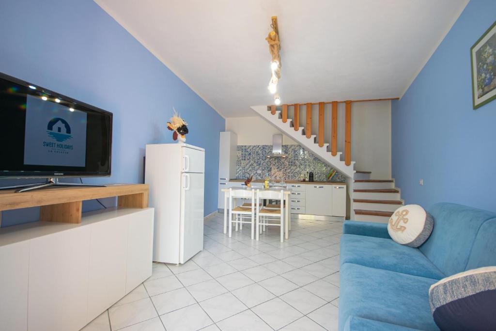 a living room with a blue couch and a kitchen at Sa Capannizza in Limpiddu