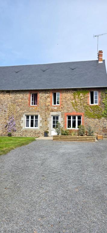 une maison en briques avec une allée en face de celle-ci dans l'établissement Gite de l'arthour, à Notre-Dame-de-Cenilly