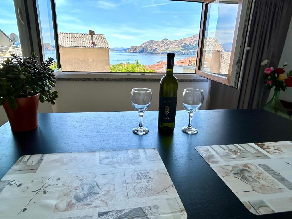 a bottle of wine sitting on a table with two glasses at Studio Neven with Sea View in Baška