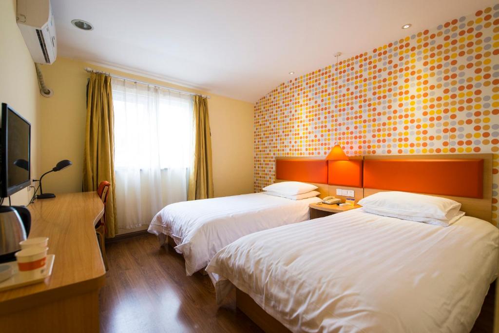 ハルビン市にあるHome Inn Harbin Sanda Dongli Road Haguoのベッド2台とテレビが備わるホテルルームです。