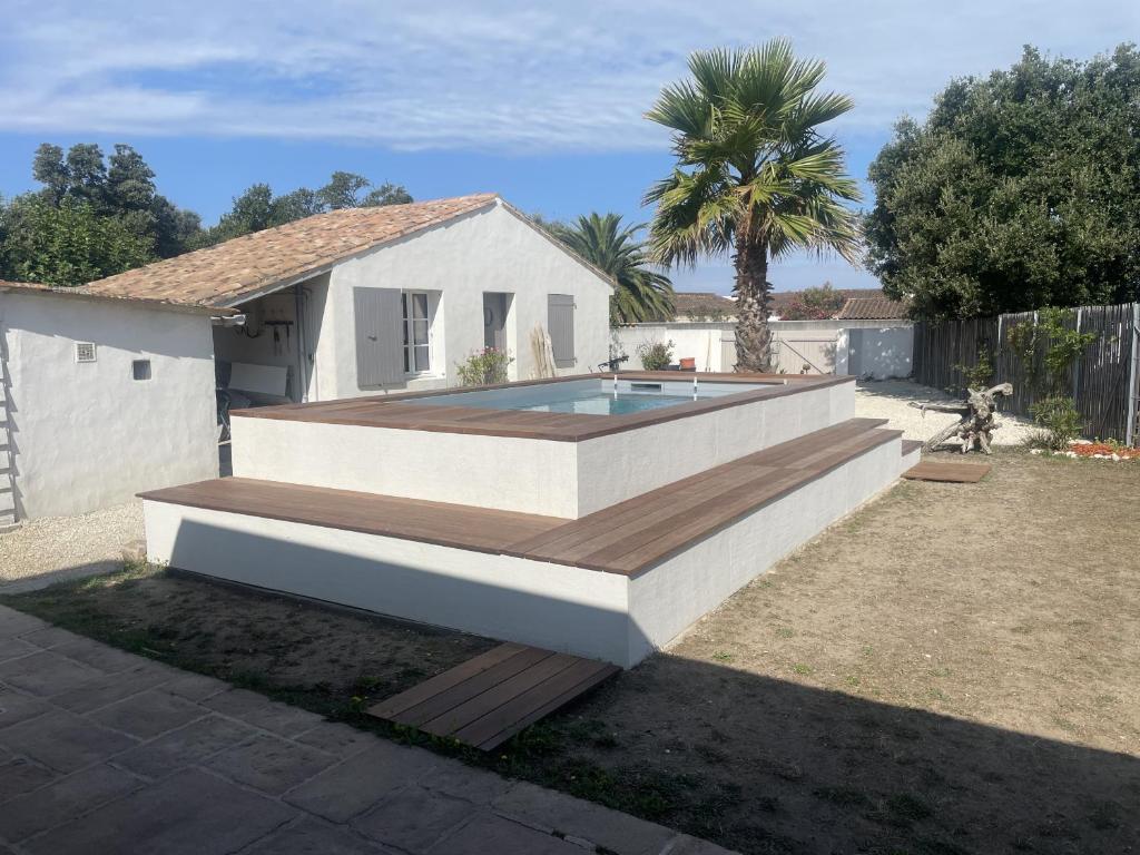una piscina con terraza de madera y una casa en La Villa du Martray, en Ars-en-Ré