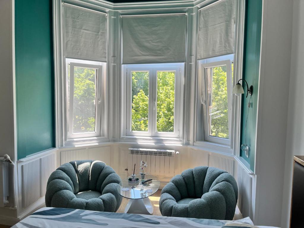 two chairs and a table in a room with windows at Livada Studio Apartments in Braşov