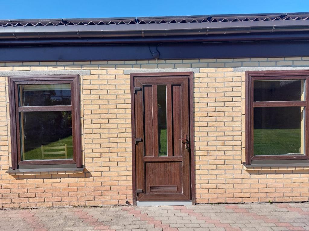 een bakstenen gebouw met een houten deur en twee ramen bij Ģimenes studija 2 in Pāvilosta
