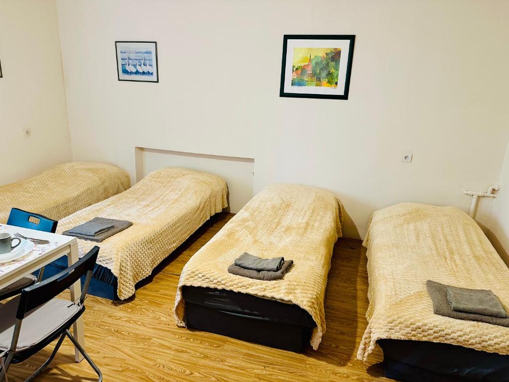 three beds in a room with a table and chairs at ANELL Hostel in Poznań