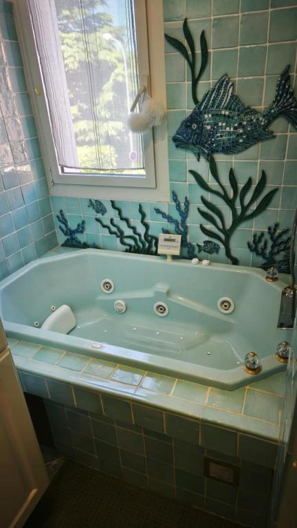 une baignoire dans une salle de bain avec une fresque de poisson dans l'établissement karine et thierry, à Arles