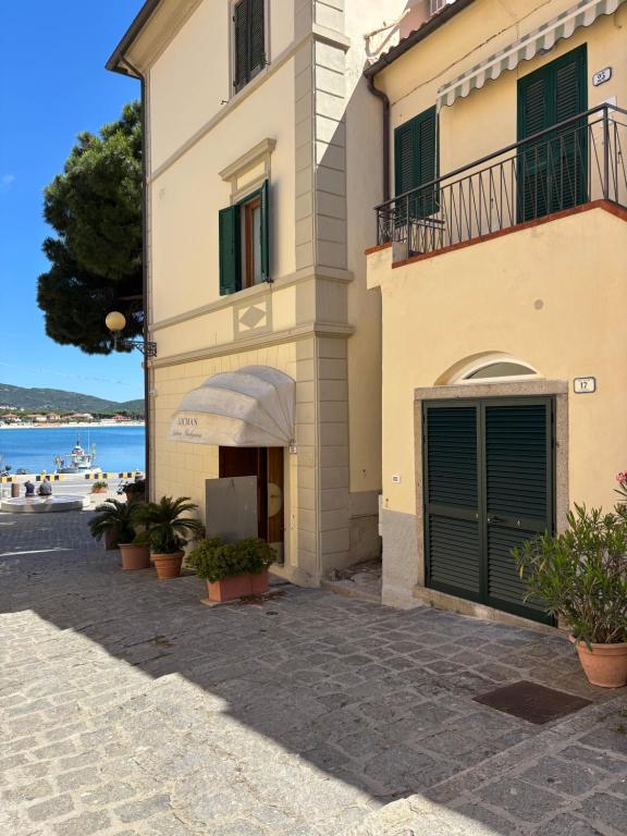 a building with green doors and a balcony at La Palamita House in Marina di Campo