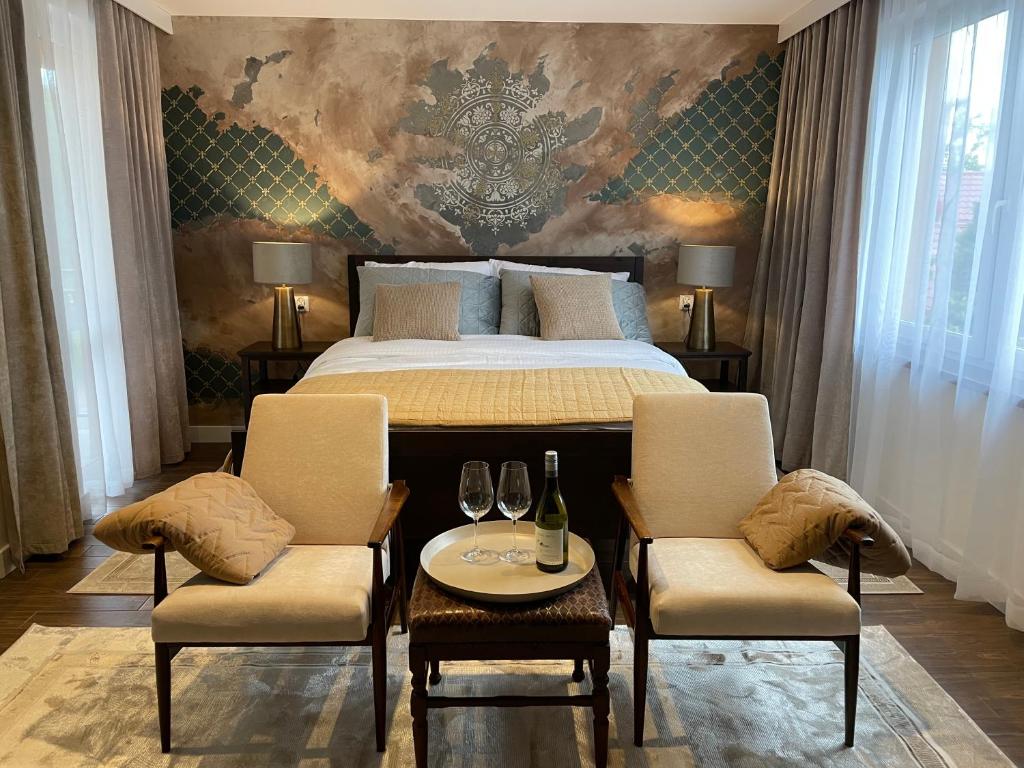a bedroom with a bed with two chairs and a table with wine glasses at Barwny Zakątek in Augustów