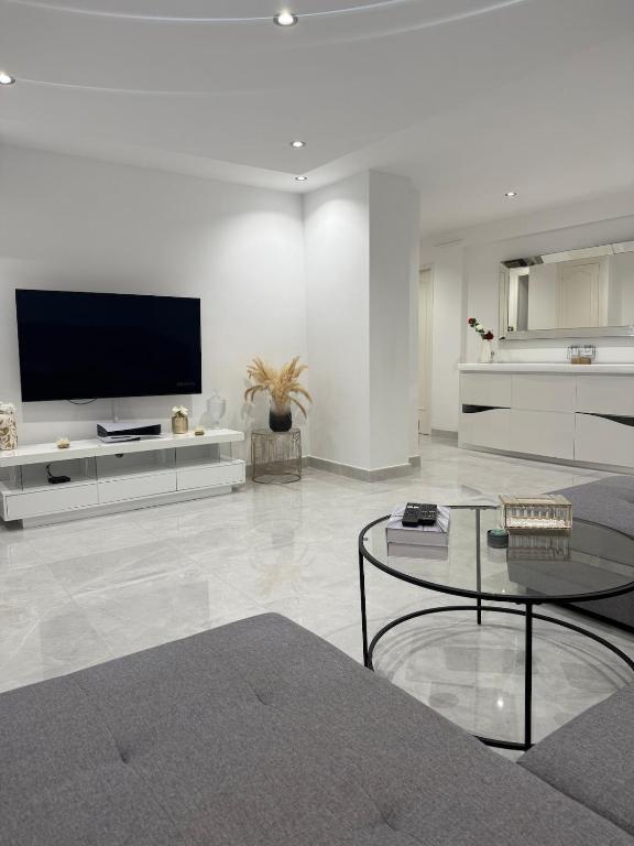 un salon blanc avec une télévision et une table dans l'établissement Le Prestigieux - plage, à Antibes