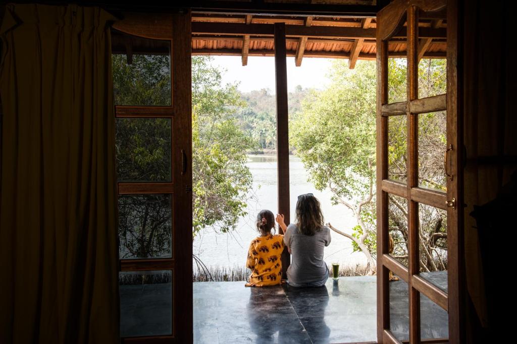 two children sitting on a porch looking out the door at The Bay Agonda in Agonda