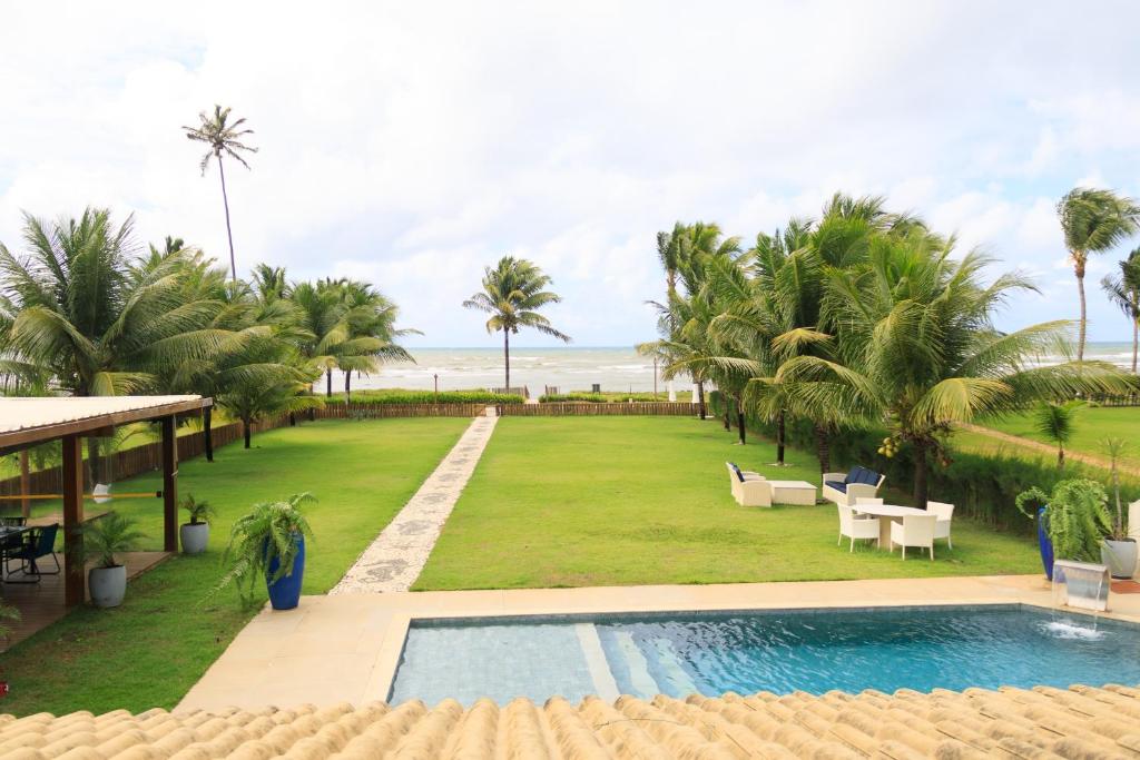 a resort with a swimming pool and a lawn with palm trees at PÉ NA AREIA, DE FRENTE PARA A PRAIA - Casa Paraíso dos Corais 8 suítes, Praia Guarajuba in Guarajuba