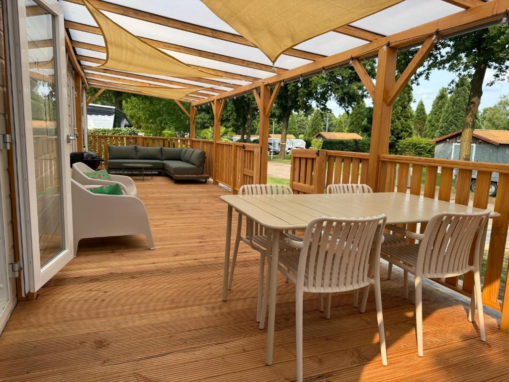 a wooden deck with a table and chairs at Luxe chalet op 5-sterren camping-4P-ruime veranda-2 fietsen in Sevenum