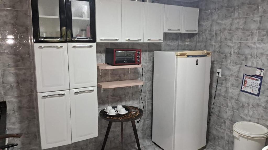 Francys Gomes في كايكو: مطبخ مع خزائن بيضاء وثلاجة