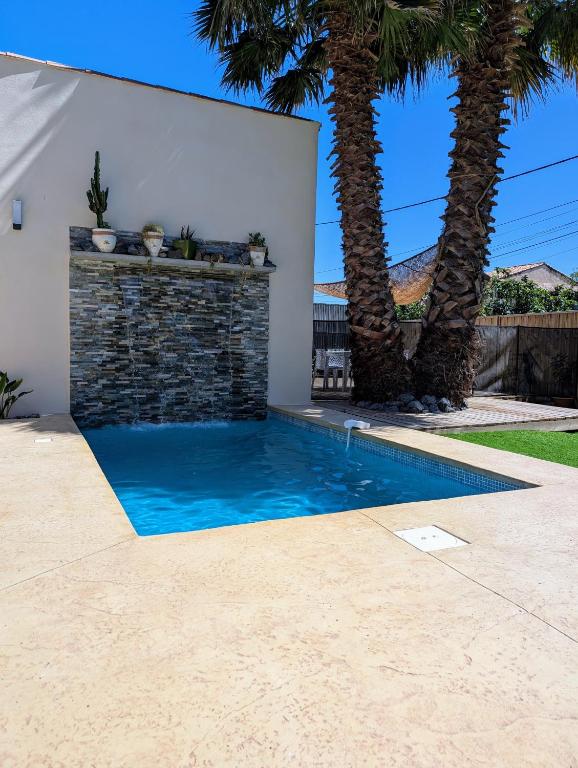 une piscine dans une cour arrière avec des palmiers dans l'établissement Villa Bali, à Tourbes