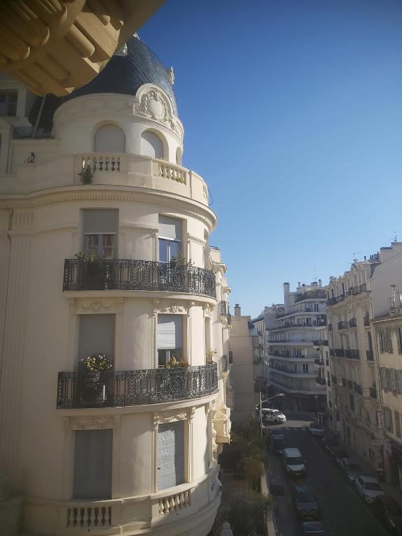 un bâtiment blanc avec un balcon sur une rue de la ville dans l'établissement Palais Clemenceau, à Nice