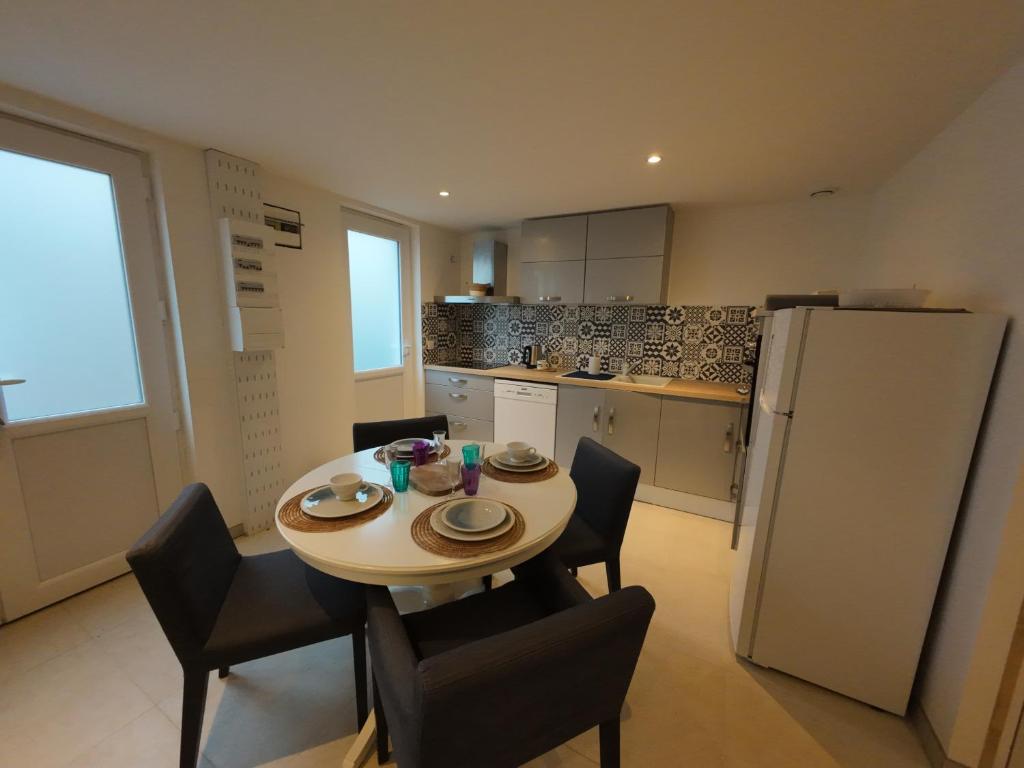 una cucina con tavolo, sedie e frigorifero di la maison bleue a La Haye-du-Puits