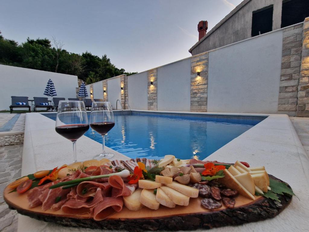 a plate of food and wine glasses next to a pool at Apartment Casa Lumina - 5 minutes to the airport and centar all private in Zvekovica