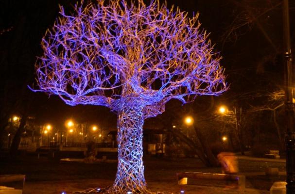 un árbol con luces moradas en él por la noche en Vītoli en Liepāja