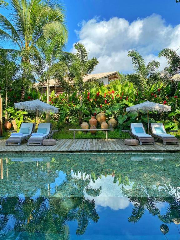 a pool with chairs and umbrellas next to a resort at Hotel Boutique Perainda in Trancoso
