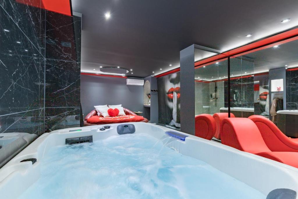a hot tub in a room with red chairs at Secret Night Pamiers in Pamiers