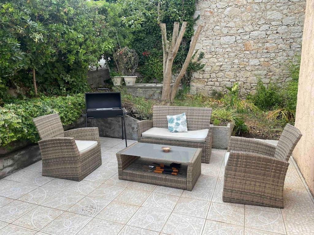 d'une terrasse avec des chaises en osier, une table et une télévision. dans l'établissement Appartement villa Magalie, à Cannes