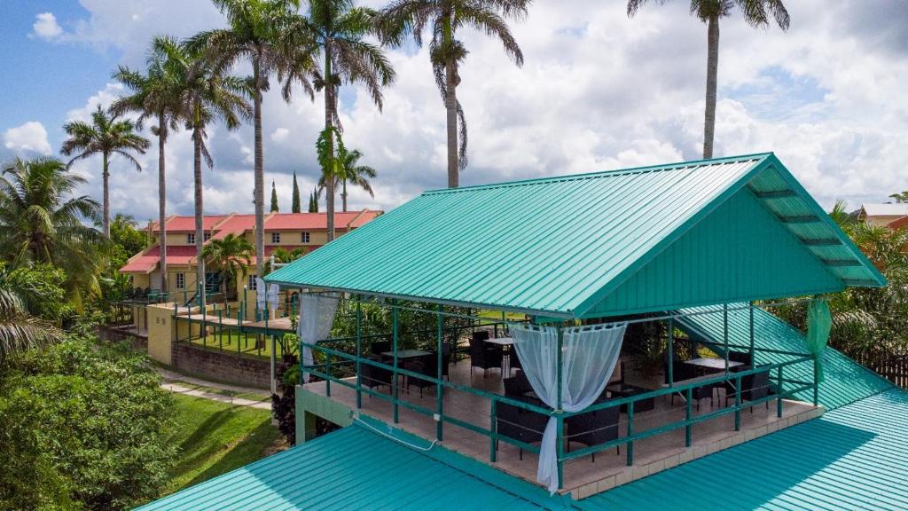 a building with a green roof and palm trees at Hill Garden Resort Hotel in San Ignacio