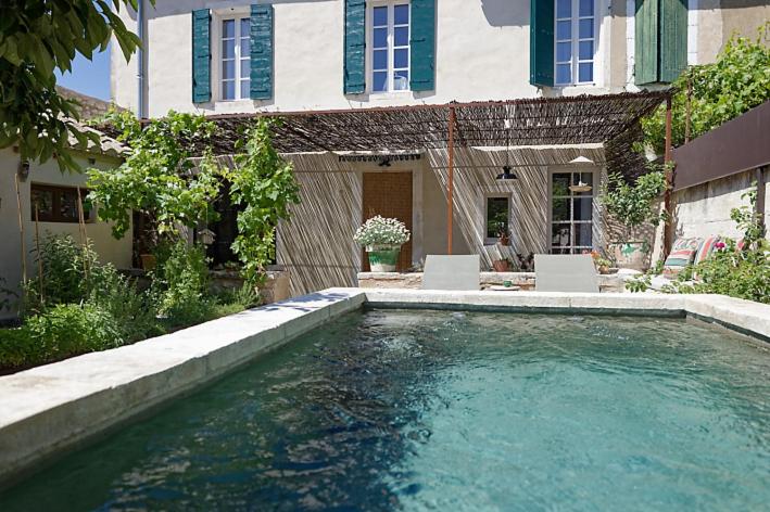 - une piscine en face d'une maison avec 2 chaises dans l'établissement Le petit Mas du village, à Saint-Rémy-de-Provence