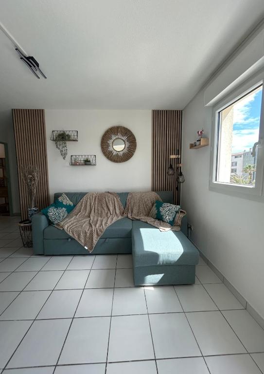 un salon avec un canapé bleu et une fenêtre dans l'établissement La casa des tortues, au Cap d'Agde
