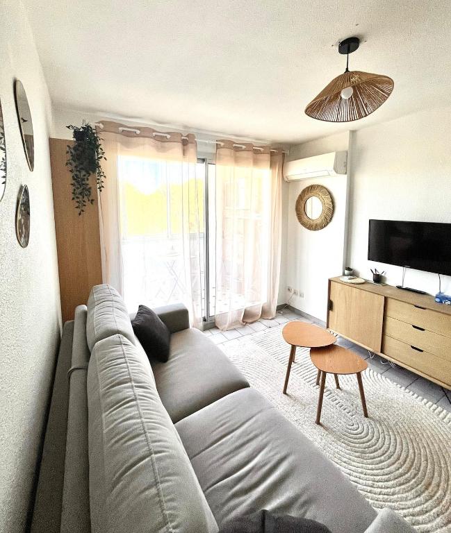 - un salon avec un grand canapé et une télévision dans l'établissement Appartement cosy à Balaruc, à Balaruc-les-Bains