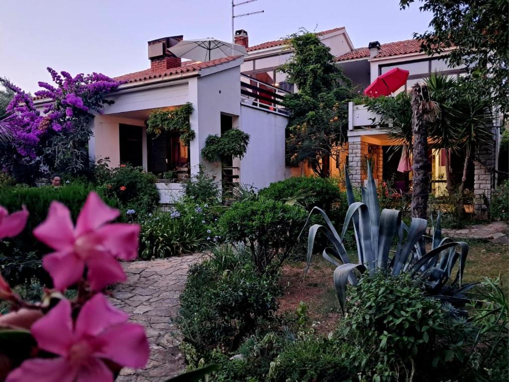 a house with pink flowers in front of it at Apartmani Jessica in Novalja