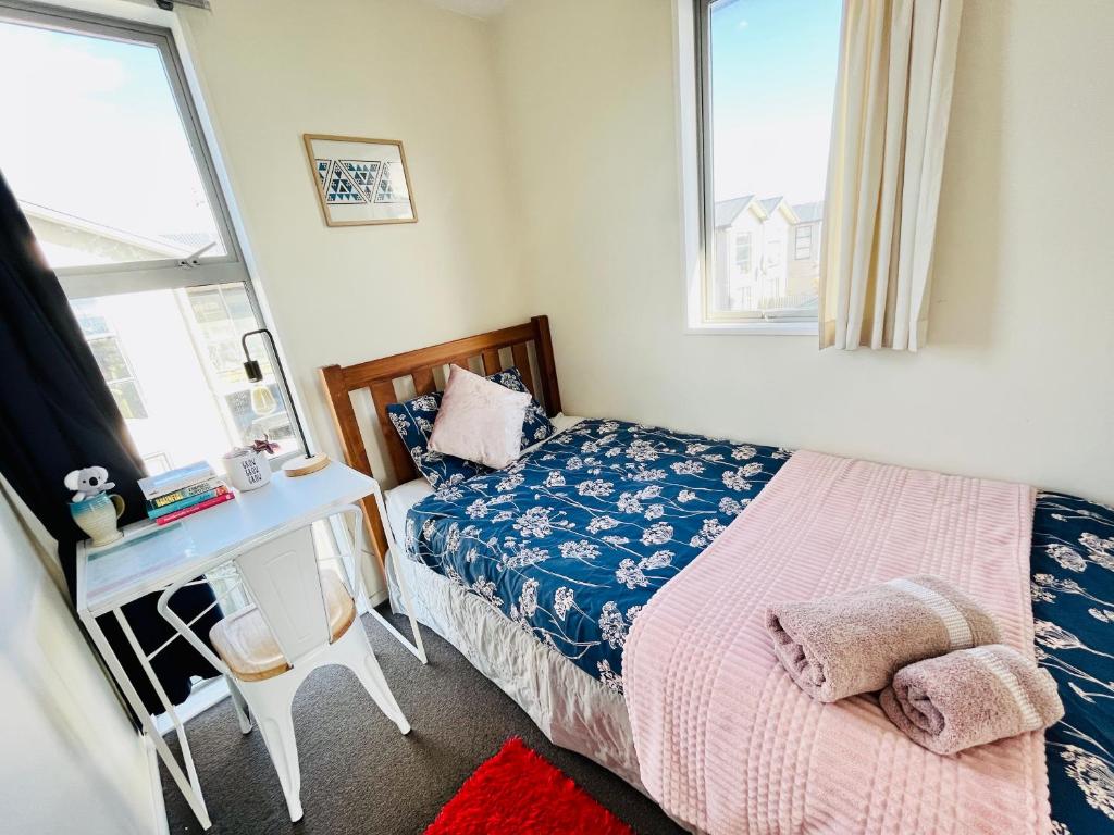 クライストチャーチにあるCity Fringe Private Room - Your Urban Escape!のベッドと机と2つの窓がある寝室