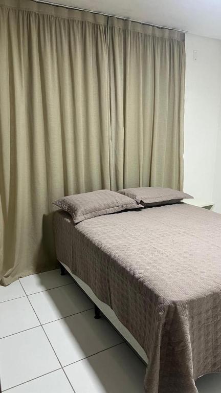 a bed in a room with a window with curtains at Apartamento 3 min do FIG in Garanhuns