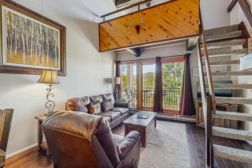 a living room with a couch and a staircase at Emerald Views at the West in Steamboat Springs