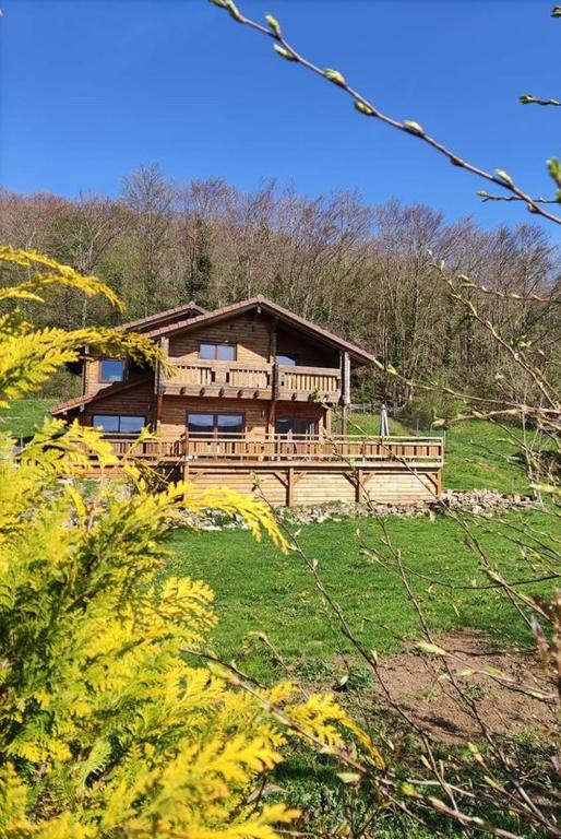 une grande maison en bois sur une colline avec des arbres dans l'établissement Chalet d'exception avec sauna et jacuzzi - vue imprenable sur la campagne, à Sainte-Blaizine