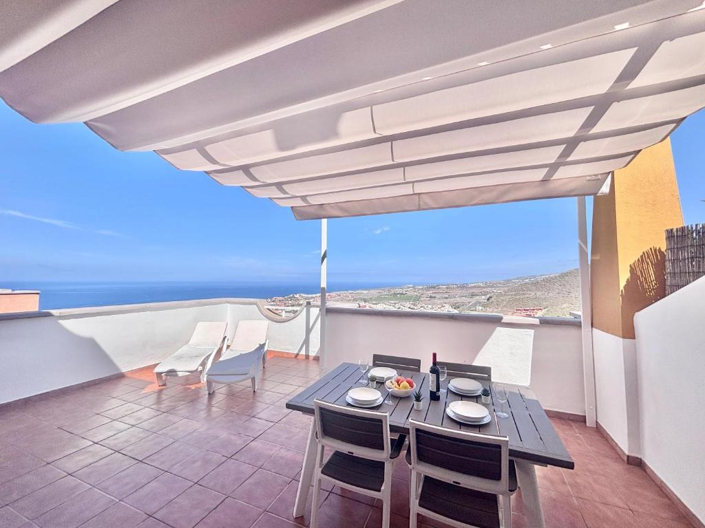 a dining room with a table and chairs on a balcony at Ocean View Haven, Perla Del Mar in Adeje