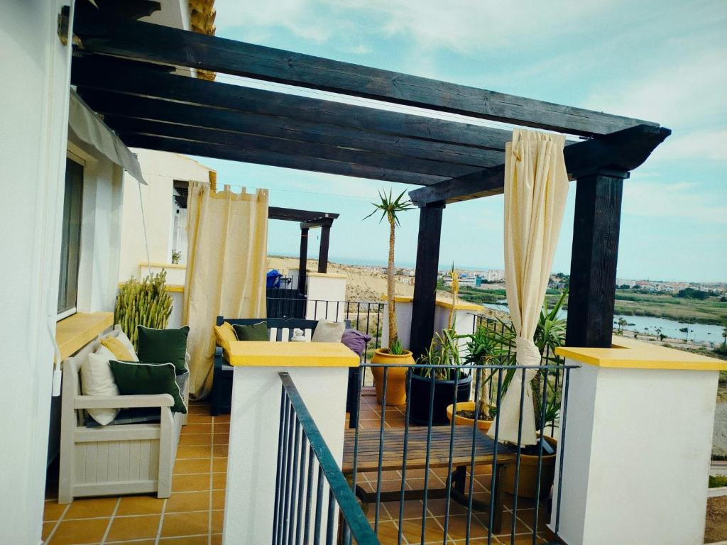 a balcony with a pergola and chairs on a house at Ático premium con vistas al mar y a la laguna del Salar in Vera