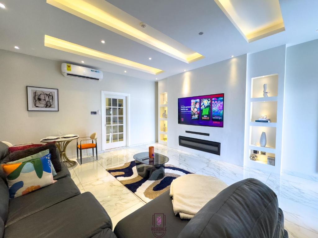 Una sala de estar con un sofá y un televisor. en ELEGANT DUPLEX @ Rosedale Apartments, en Accra