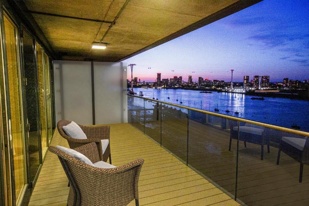 a balcony with chairs and a view of a river at Waterfront- London Greenwich o2 Arena 2 Bed Flat in London