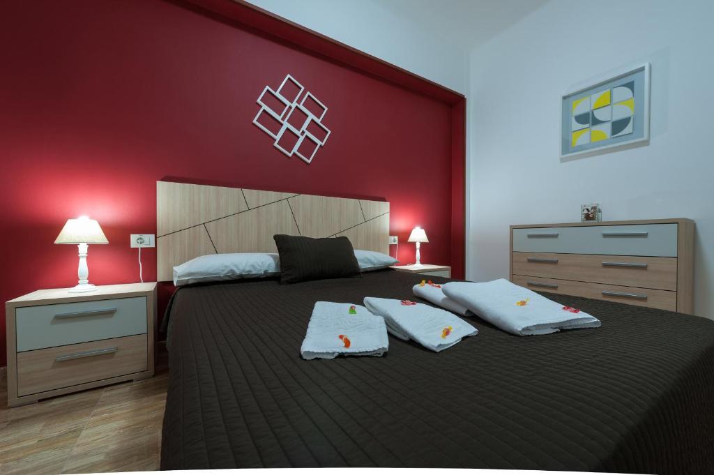 1 dormitorio con 1 cama grande y pared roja en Apartamentos Vacacionales Las Palmas Urban Center, en Las Palmas de Gran Canaria