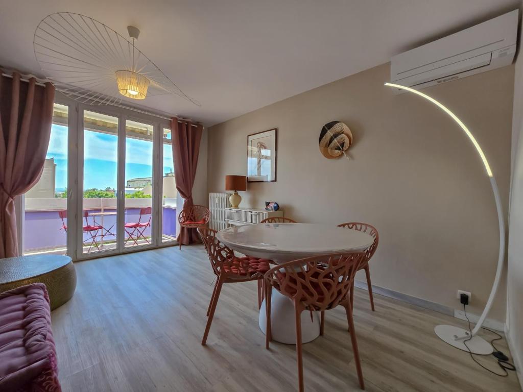 un salon avec une table et des chaises et un balcon dans l'établissement L'Heure Sud T3 T3 clim avec garage au centre-ville, à Hyères