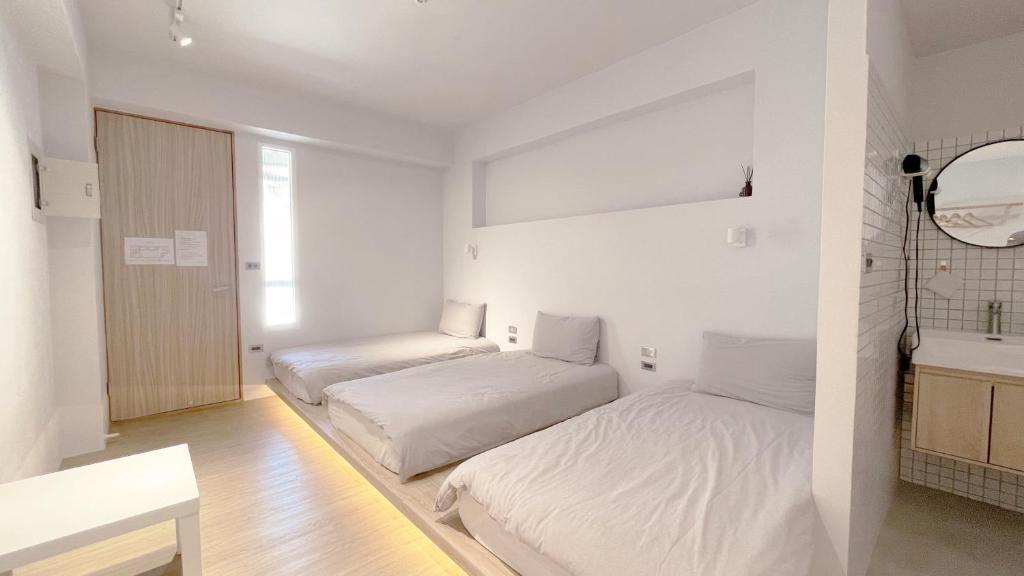 zwei Betten in einem Zimmer mit weißen Wänden in der Unterkunft 落跑吧民宿 in Taitung