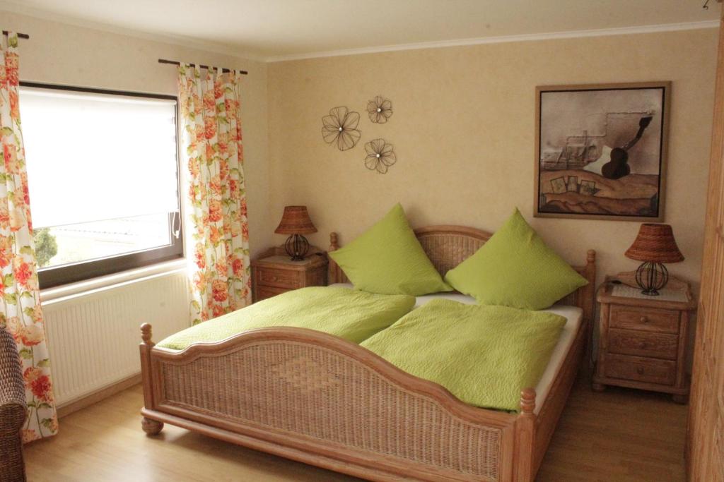 Schlafzimmer mit einem Bett mit grüner Bettwäsche und einem Fenster in der Unterkunft Ferienwohnung Erika in Wimbach